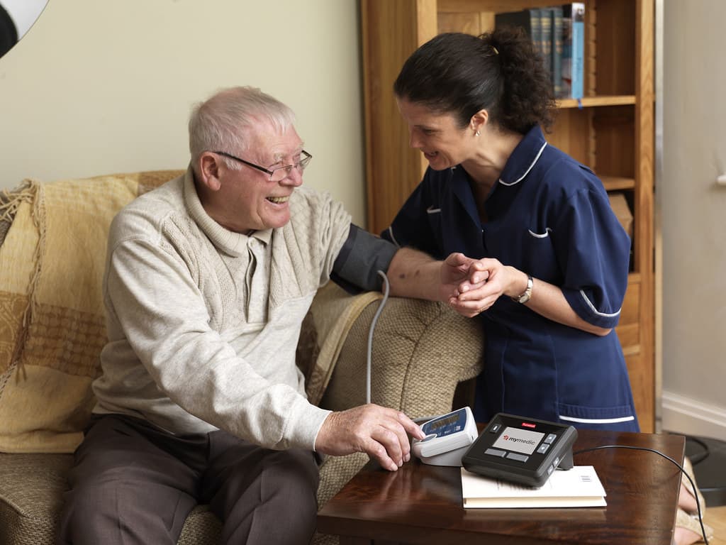 Older man checking blood pressure with a nurse during a telehealth session